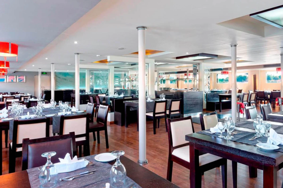 The restaurant on the Nile Premium Nile cruise, dark timber tables laid with glassware between white columns