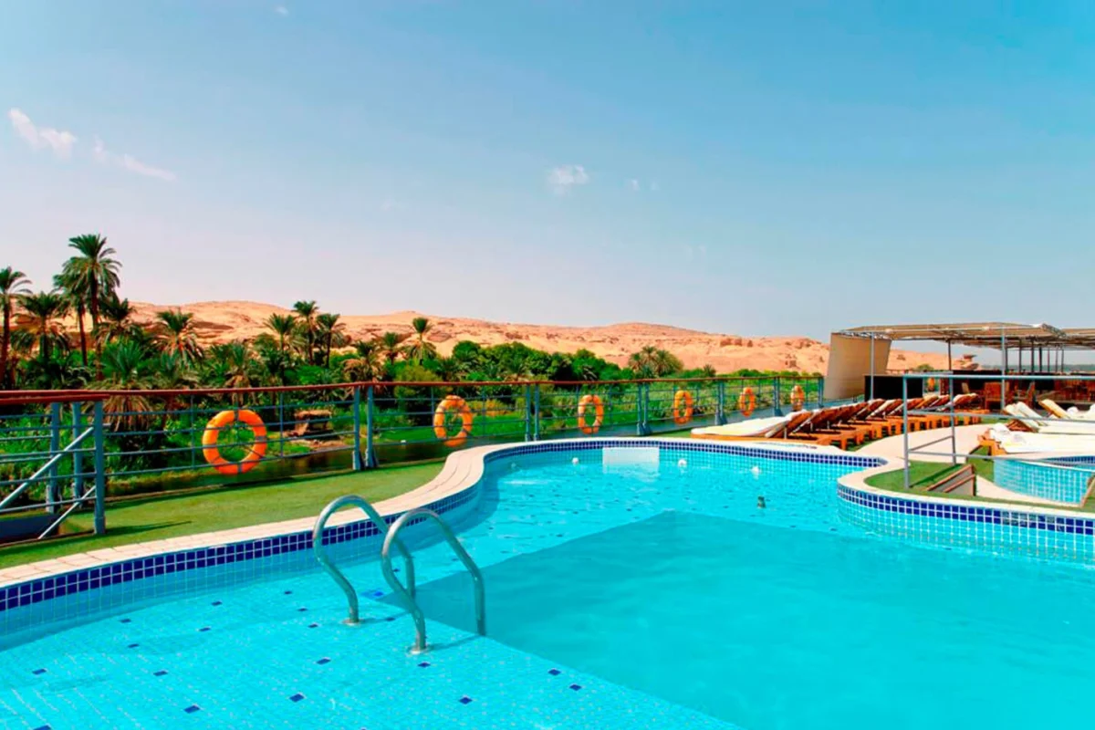 The swimming pool on the Nile Premium Nile cruise sun deck, palms and desert dunes rising along the far bank