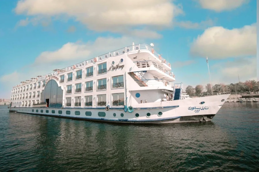 The Nile Story Nile cruise ship on the Nile, its white hull and arched superstructure seen from the bow quarter