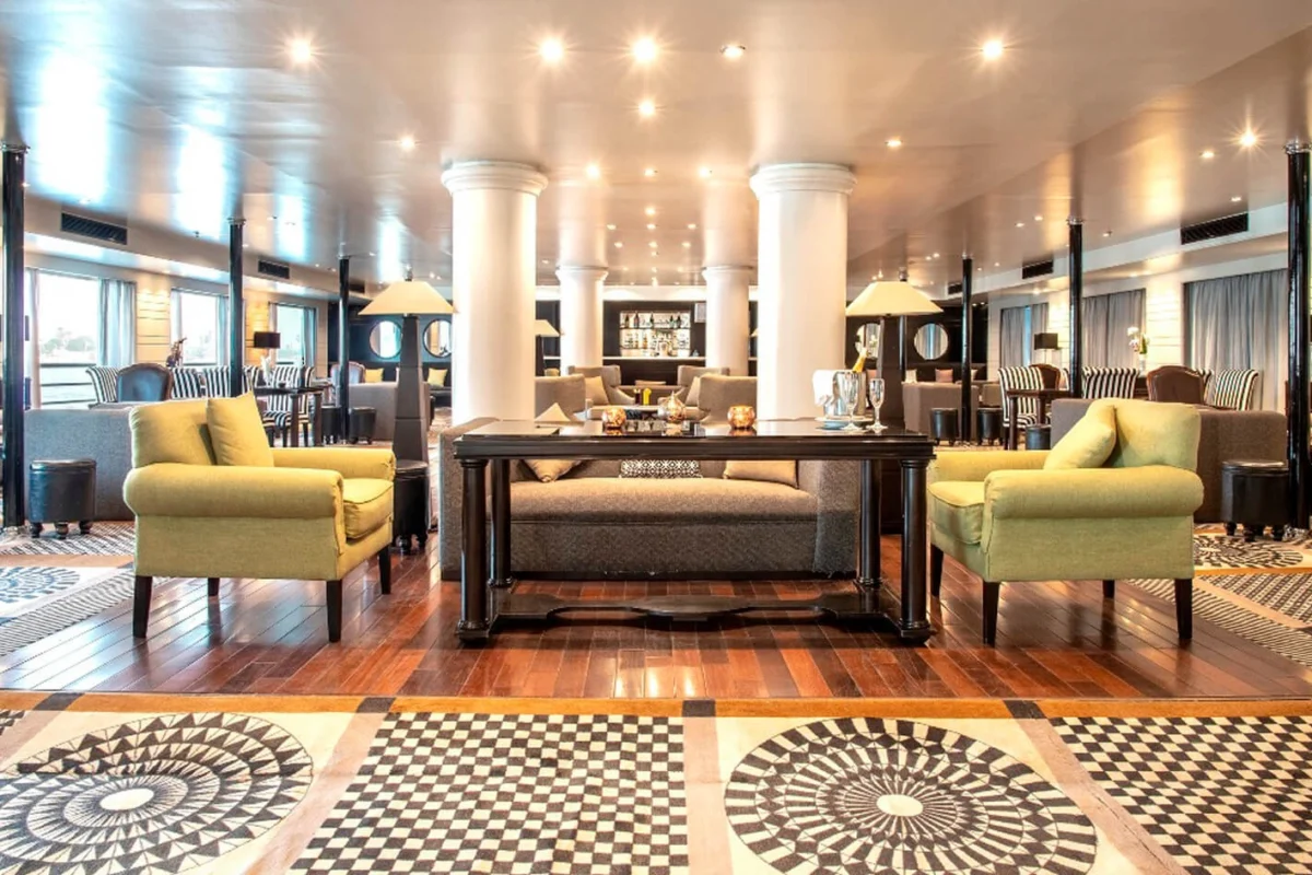 The lounge on the Nile Style Nile cruise, yellow armchairs and dark tables on a patterned floor between white columns