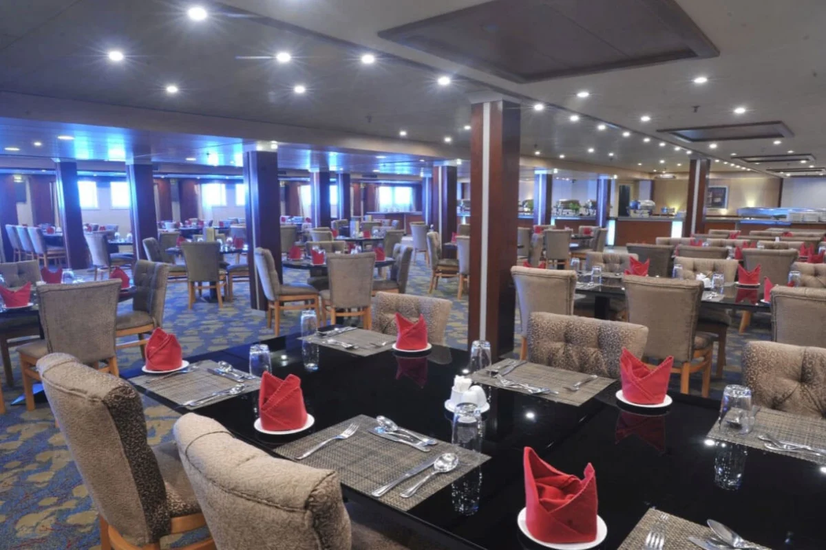 The restaurant on the Royal Esadora Nile cruise, tables laid with red napkins beneath bright ceiling lights