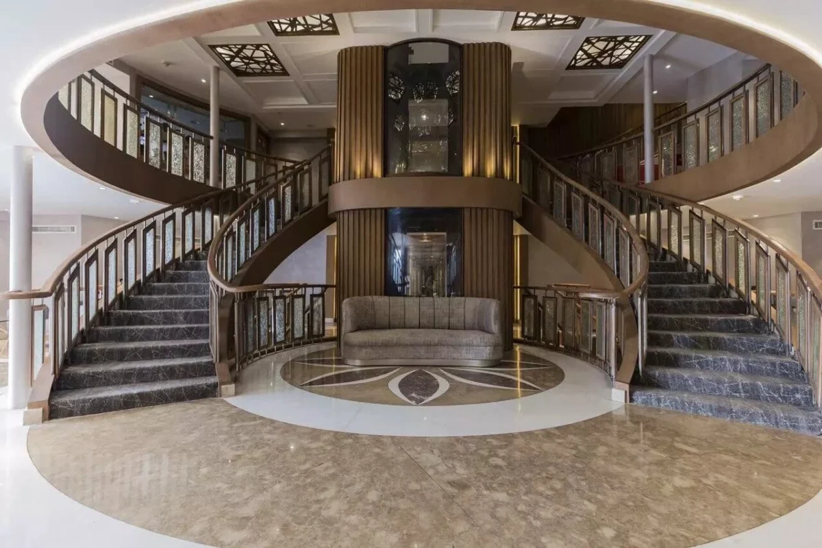 The twin curved staircase of the Semramis II Nile cruise atrium, a glass lift rising between them