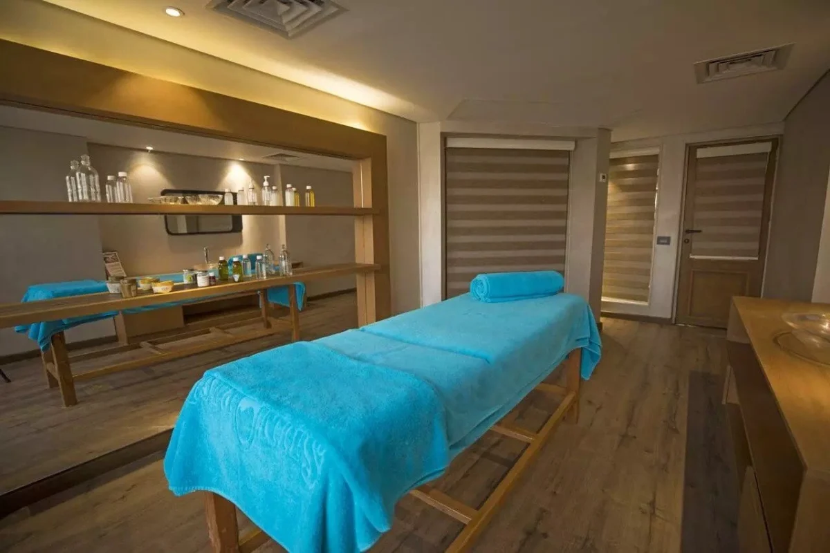 A massage table dressed in turquoise in the Semramis II Nile cruise spa, oils on the shelf behind