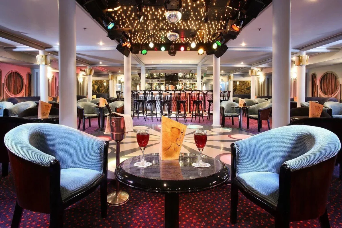 The bar on the Sonesta Moon Goddess Nile cruise, blue tub chairs at a table with drinks and the counter behind