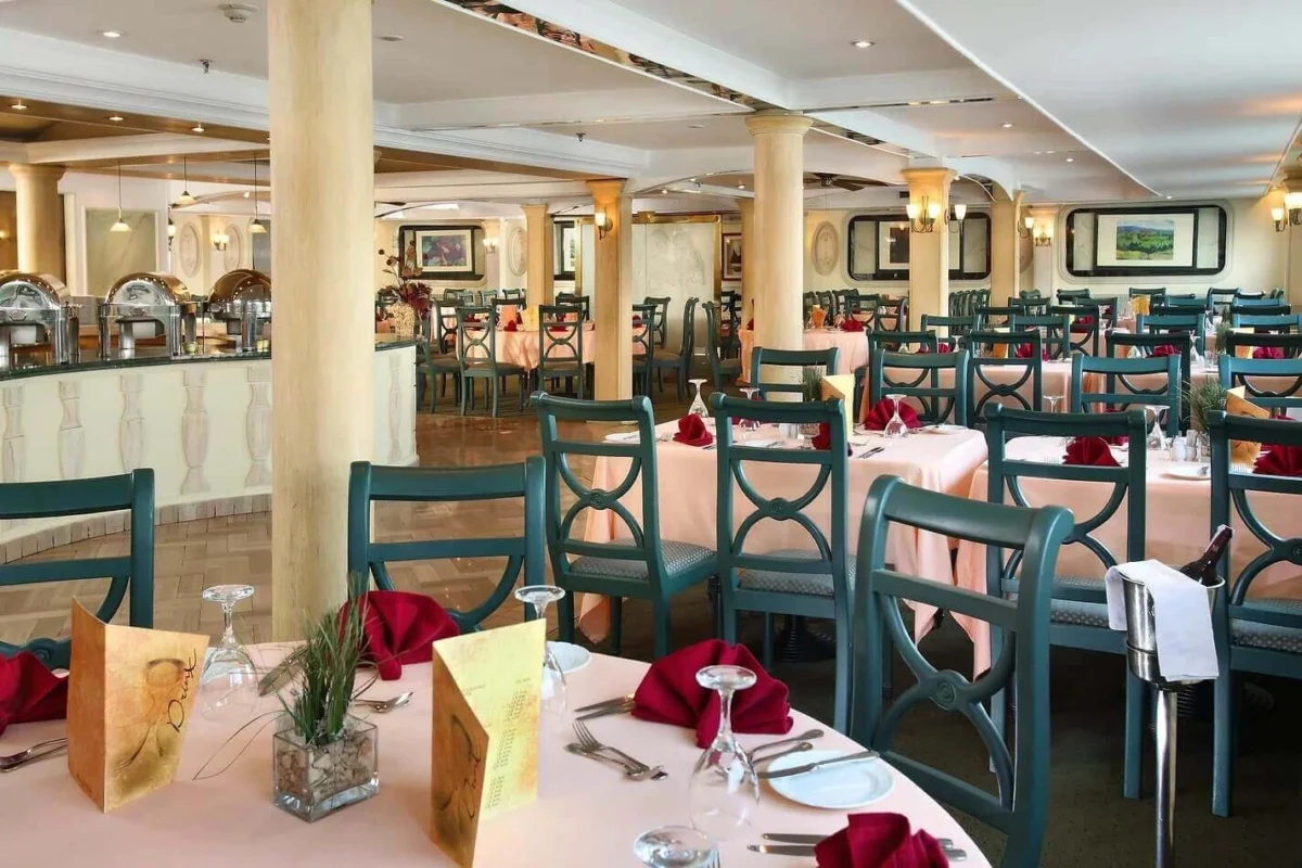 The restaurant on the Sonesta Moon Goddess Nile cruise, tables laid with red napkins and blue-backed chairs