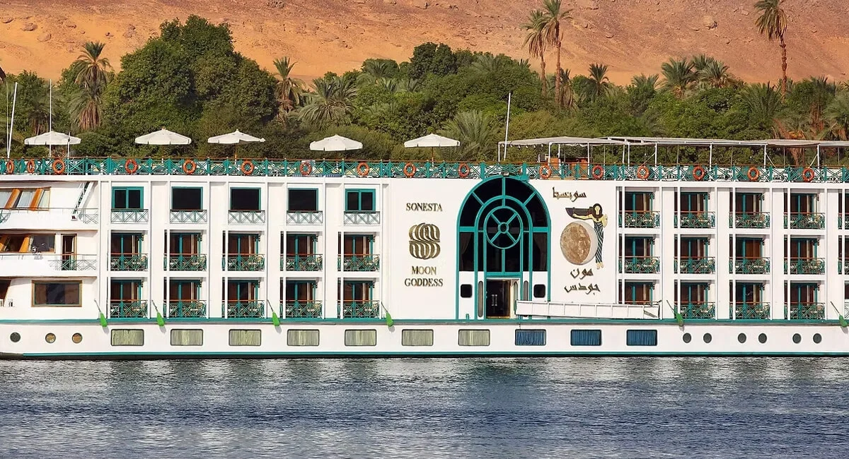 The Sonesta Moon Goddess Nile cruise ship broadside on the Nile, its arched entrance amidships