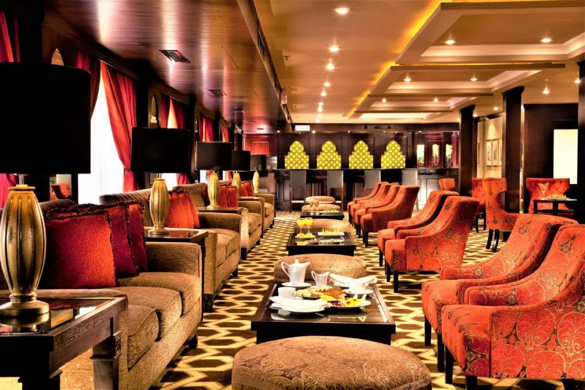 The lounge on the Steigenberger Legacy Nile cruise, red armchairs and sofas down both sides of a patterned carpet