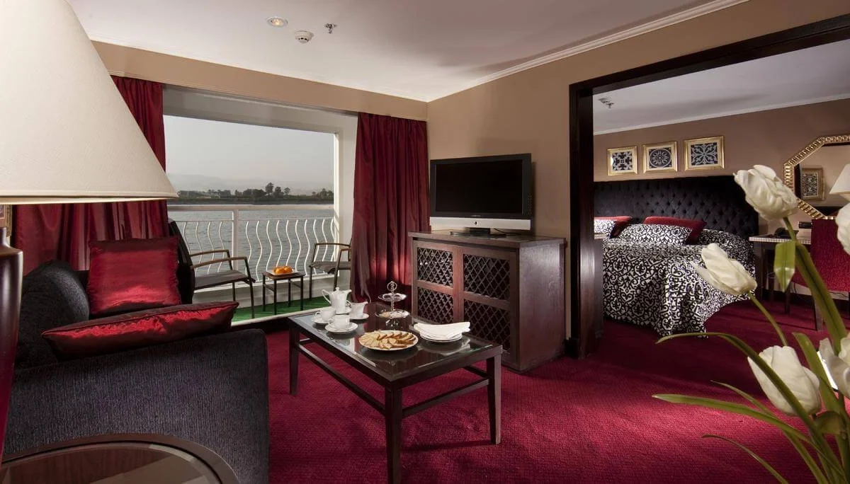 A suite on the Steigenberger Minerva Nile cruise, a sitting area in red beside the bedroom with a river window