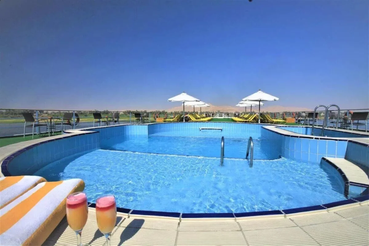 The swimming pool on the Steigenberger Royale Nile cruise sun deck, two juices on the ledge and parasols beyond
