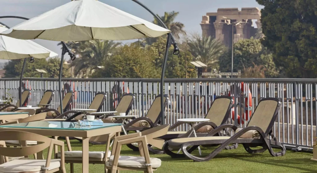 Sun loungers and shaded tables on the Tulip Nile cruise sun deck, with a temple colonnade visible on the bank beyond